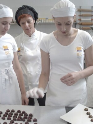 Skupina dijakinj slaščičarstva pri izdelovanju čokoladnih pralin, pod vodstvom mentorice