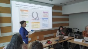 Predavateljica predstavlja model področij kakovosti in samoevalvacije v izobraževanju. Na projekciji je shematski prikaz kakovostne arhitekture.