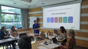 Predavateljica predstavlja okvir kakovosti za šole z diagramom samoevalvacije na projekcijskem platnu. Udeleženci spremljajo predstavitev in zapisujejo ugotovitve.